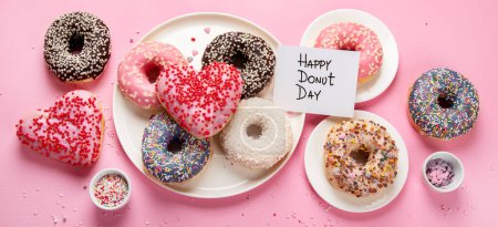 Photo for Donuts doughnuts with chocolate, marshmallow and sugar sprinkles on pink background, top view. Colorful carnival or birthday party card. Happy National donut day Concept. Panorama. - Royalty Free Image