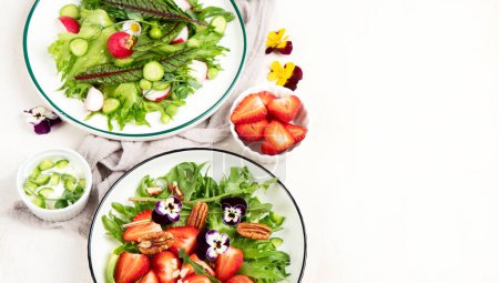 Foto de Deliciosas ensaladas de primavera con flores comestibles, verduras, frutas, microverduras y queso sobre un fondo blanco. Concepto de alimentación limpia y saludable. Vista superior. Copiar espacio. - Imagen libre de derechos