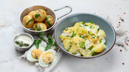 Foto de Ensalada de papas, huevos, cebollas verdes y mayonesa en un plato sobre fondo blanco, vista superior - Imagen libre de derechos