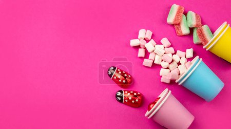 Foto de Surtido de caramelos de jalea dulce multicolor y malvaviscos en copas ecológicas sobre fondo rosa. Vista superior. Copiar espacio. - Imagen libre de derechos
