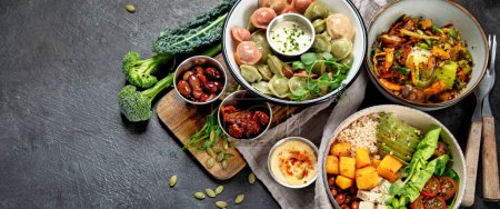 Photo for Healthy vegetarian and vegan dumplings and Buddha Bowls with vitamins, antioxidants, protein on dark background. Top view. Panorama with copy space. - Royalty Free Image
