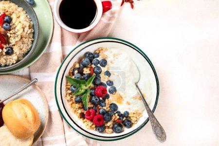 Photo for Breakfast food table. Healthy breakfast or brunch set, meal variety with granola, porridge, cornflakes, fresh berries, fruits and various of topping on a white background. Top view. Copy space. - Royalty Free Image