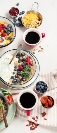 Photo for Breakfast food table. Healthy breakfast or brunch set, meal variety with granola, porridge, cornflakes, fresh berries, fruits and various of topping on a white background. Top view. - Royalty Free Image
