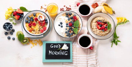 Photo for Breakfast food table. Healthy breakfast or brunch set, meal variety with granola, porridge, cornflakes, fresh berries, fruits and various of topping on a white background. Top view. Panorama. - Royalty Free Image
