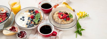 Photo for Breakfast food table. Healthy breakfast or brunch set, meal variety with granola, porridge, cornflakes, fresh berries, fruits and various of topping on a white background. Top view. Panorama with copy space. - Royalty Free Image