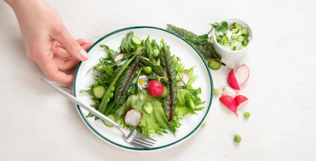 Téléchargez les photos : Salade vitaminée printanière. Salade de légumes frais et d'herbes. Concept de saine alimentation. Vitamines pour l'immunité. Nourriture pour végétariens sur fond blanc. Vue du dessus. - en image libre de droit