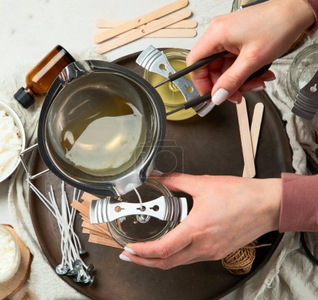 Téléchargez les photos : Set pour bougies de cire de soja écologique naturel fait maison, femme faisant bougie d'arôme décoratif à la table - en image libre de droit