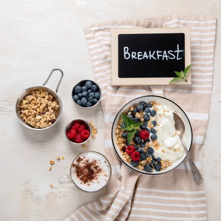 Foto de Granola con yogur y bayas para un desayuno saludable. Cuenco de yogur griego con granola, arándanos y frambuesas sobre un fondo blanco, vista superior. - Imagen libre de derechos