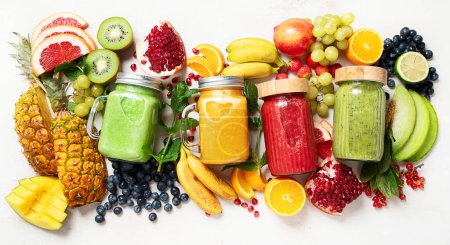 Foto de Batidos de frutas y verduras frescas o zumos con varios ingredientes sobre fondo claro. Vista superior - Imagen libre de derechos
