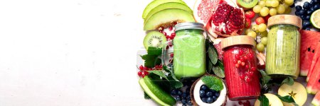 Téléchargez les photos : Smoothies ou jus de fruits et légumes frais avec divers ingrédients sur fond clair. Vue du dessus, espace de copie, panorama, bannière - en image libre de droit