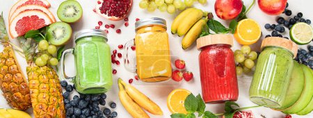 Téléchargez les photos : Smoothies ou jus de fruits et légumes frais avec divers ingrédients sur fond clair. Vue de dessus, panorama, bannière - en image libre de droit
