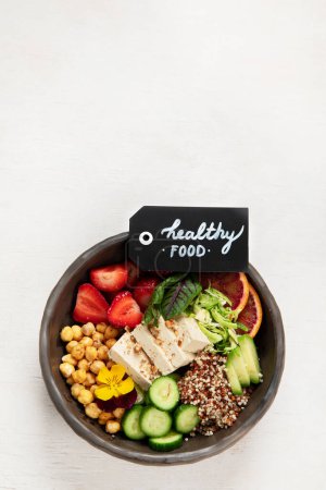 Photo for Healthy vegan lunch bowl. Avocado, quinoa, cucumber, red orange, chickpea, cheese, salad and strawberries on a white background. Top view. Copy space. - Royalty Free Image