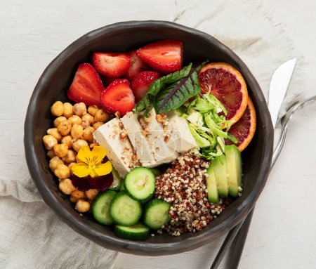 Photo for Healthy vegan lunch bowl. Avocado, quinoa, cucumber, red orange, chickpea, cheese, salad and strawberries on a white background. Top view. - Royalty Free Image