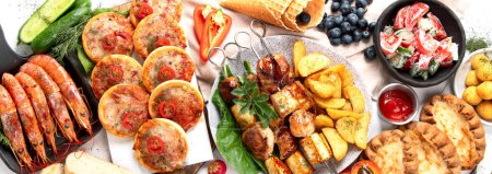 Photo for Summer picnic food, grilled meat, kebab, vegetable salad, fruit salad, pizza, sandwiches and snacks on a white background. Top view. Panorama. - Royalty Free Image