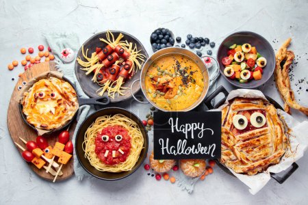 Téléchargez les photos : Fun Halloween dîner scène de table de fête sur un fond gris. Vue de dessus. Pizza, tarte, spaghettis et collations - en image libre de droit