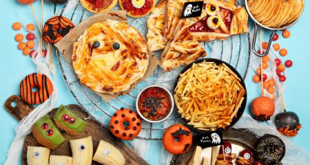 Téléchargez les photos : Fun Halloween dîner scène de table de fête sur un fond bleu. Vue de dessus. Pizza, tarte, spaghettis et collations - en image libre de droit