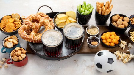 Téléchargez les photos : Snacks salés et de la bière pour le temps de football sur un fond blanc. Vue du dessus. - en image libre de droit