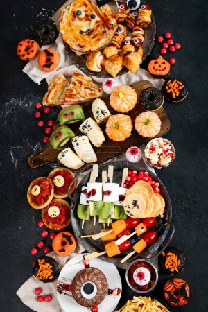 Foto de Divertida cena de Halloween escena de mesa sobre un fondo gris. Vista superior. Pizza, tarta, espaguetis y aperitivos. - Imagen libre de derechos