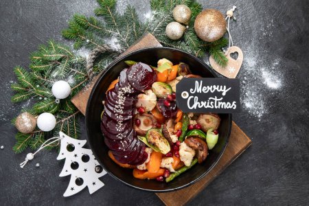 Téléchargez les photos : Légumes grillés, rôtis et cuits dans une casserole sur un fond sombre. Betterave, carotte, champignons, citrouille et choux de Bruxelles. Déjeuner de Noël, dîner de Noël végétarien, vue sur le dessus. - en image libre de droit