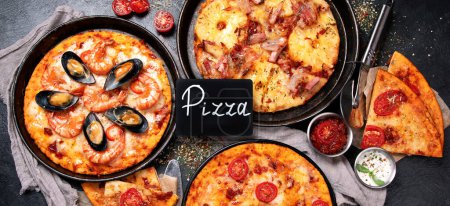 Foto de Surtido de varios tipos de pizza italiana sobre un fondo negro, vista superior. Panorama. - Imagen libre de derechos