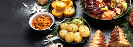 Photo for Vegan food with brussels sprouts, carrots, cauliflower, mushrooms, avocado, cake on a dark background, top view. Vegetarian Christmas dinner, healthy food. Panorama with copy space. - Royalty Free Image