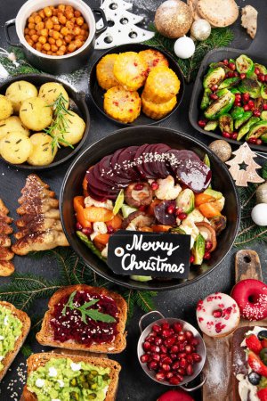 Photo for Vegan food with brussels sprouts, carrots, cauliflower, mushrooms, avocado, cake on a dark background, top view. Vegetarian Christmas dinner, healthy food. - Royalty Free Image