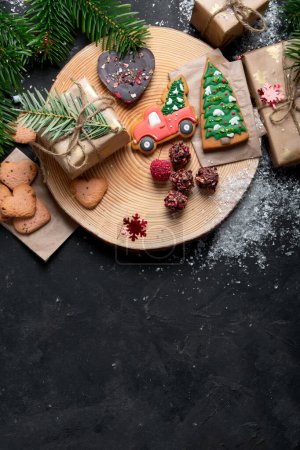 Photo for Christmas mix cookies, traditional Xmas chocolate Gingerbreads with holiday decoration, gifts, Christmas tree branch on dark backgrount, top view. Copy space. - Royalty Free Image