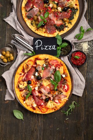 Téléchargez les photos : Pizzas chaudes et savoureuses prêtes à manger. Pizza faite maison avec Pepperoni et bacon sur un fond en bois, vue sur le dessus. - en image libre de droit