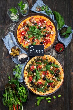 Photo for Italian pizzas with pesto and tomato sauce. Delicious vegan pizzas on black background. Top view. - Royalty Free Image