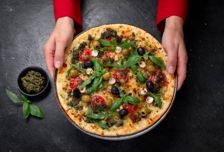 Foto de Pizza Margherita con tomates, queso, albahaca y aceitunas sobre fondo negro. Pizza vegetariana fina casera. Vista superior. - Imagen libre de derechos