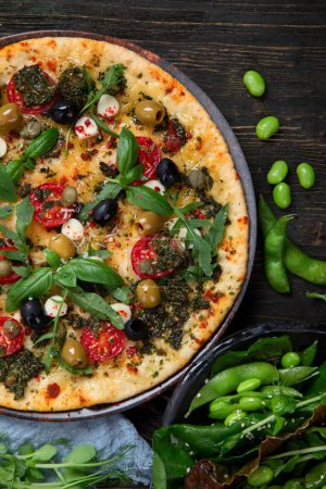 Téléchargez les photos : Pizzas italiennes au pesto et sauce tomate. Délicieuses pizzas végétaliennes sur fond noir. Vue du dessus. - en image libre de droit