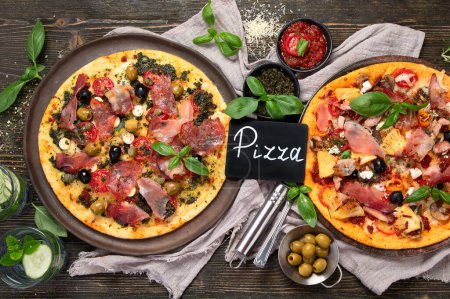 Photo for Hot tasty pizzas ready to eat. Homemade Meat Lovers Pizza with Pepperoni and Bacon on a wooden background, top view. - Royalty Free Image
