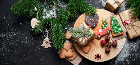 Photo for Christmas mix cookies, traditional Xmas chocolate Gingerbreads with holiday decoration, gifts, Christmas tree branch on dark backgrount, top view. Panorama with copy space. - Royalty Free Image