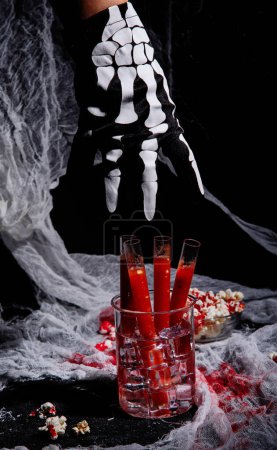 Foto de Sangriento cóctel en tubos de vidrio para la celebración de la fiesta de Halloween con aperitivos sobre un fondo negro. - Imagen libre de derechos