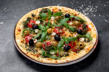Téléchargez les photos : Pizza Margherita aux tomates, fromage, basilic et olives sur fond noir. Pizza végétarienne fine maison. Vue du dessus. - en image libre de droit