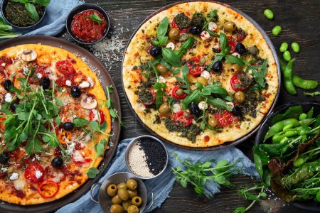 Foto de Pizzas italianas con pesto y salsa de tomate. Deliciosas pizzas veganas sobre fondo negro. Vista superior. - Imagen libre de derechos