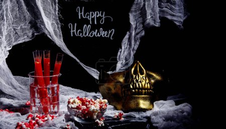 Téléchargez les photos : Cocktail sanglant en tubes de verre pour la fête d'Halloween avec des collations sur fond noir. - en image libre de droit