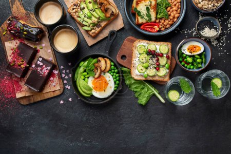 Photo for Tasty food with avocado toast, vegetables, eggs on dark background. Helthy breakfast concept. Top view, copy space. - Royalty Free Image