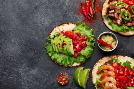 Téléchargez les photos : Tacos avec salsa, légumes et avocat sur fond noir. Espace de copie. - en image libre de droit