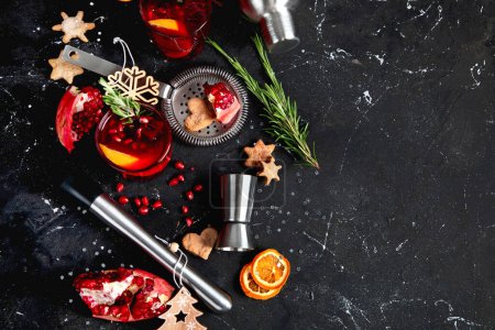 Téléchargez les photos : Cocktail de Noël d'hiver avec grenade et romarin dans un verre sur fond noir. Vue du dessus. - en image libre de droit