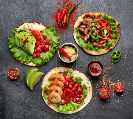 Foto de Tacos con salsa, verduras y aguacate sobre fondo negro - Imagen libre de derechos