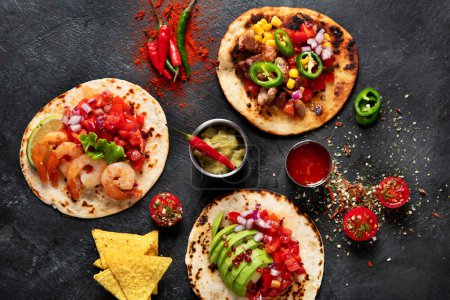 Foto de Tacos con salsa, verduras y aguacate sobre fondo negro. - Imagen libre de derechos