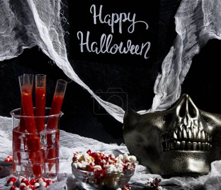 Foto de Sangriento cóctel en tubos de vidrio para la celebración de la fiesta de Halloween con aperitivos sobre un fondo negro. - Imagen libre de derechos