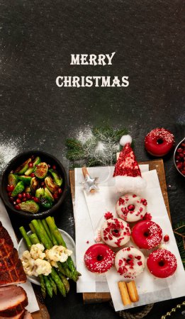 Foto de Jamón al horno con verduras y rosquillas sobre fondo oscuro. Comida navideña. Vista superior. Copiar espacio. - Imagen libre de derechos