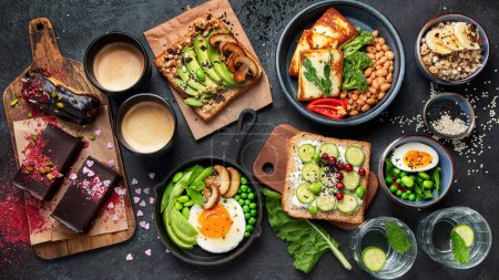 Photo for Tasty food with avocado toast, vegetables, eggs on dark background. Helthy breakfast concept. Top view. - Royalty Free Image