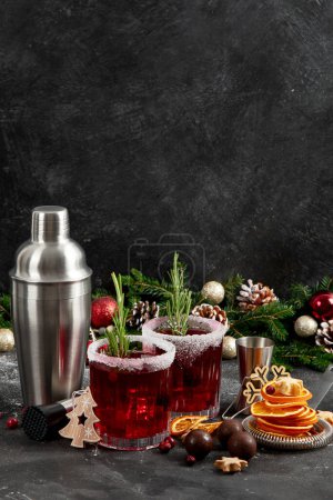 Photo for Cranberry christmas cocktail with rosemary served on winter holidays decorated table on a dark background. Front view. - Royalty Free Image