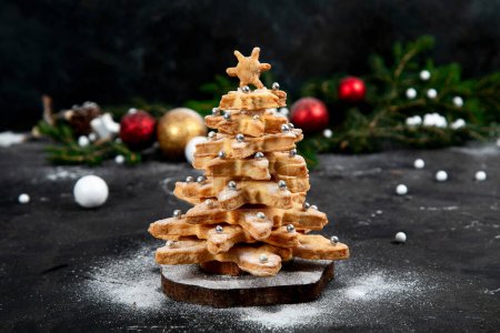 Photo for Homemade Gingerbread cookies. Christmas tree, decorated with icing and sugar decorations on a black background. Top view. - Royalty Free Image