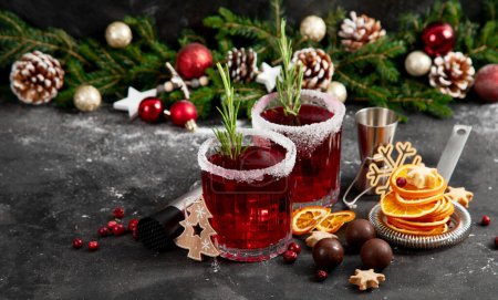 Téléchargez les photos : Cocktail de Noël aux canneberges avec romarin servi pendant les vacances d'hiver table décorée sur fond sombre. Vue de face. - en image libre de droit