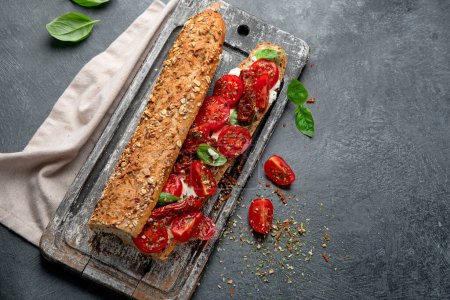 Photo for Fresh baguette with Caprese. Delicious sandwich with with tomatoes and mozzarella cheese with fresh basil leaves. Italian food conception. Top view, copy space. - Royalty Free Image