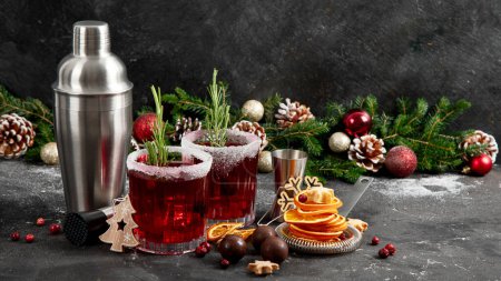 Photo for Cranberry christmas cocktail with rosemary served on winter holidays decorated table on a dark background. Front view. - Royalty Free Image